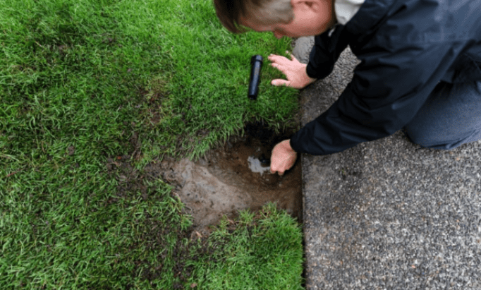 person outside touching sprinkler